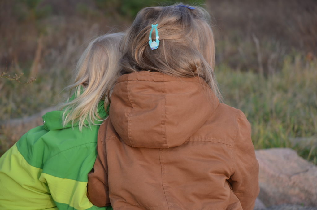 zwei Kinder von hinten in der Natur mit Winterkleidung