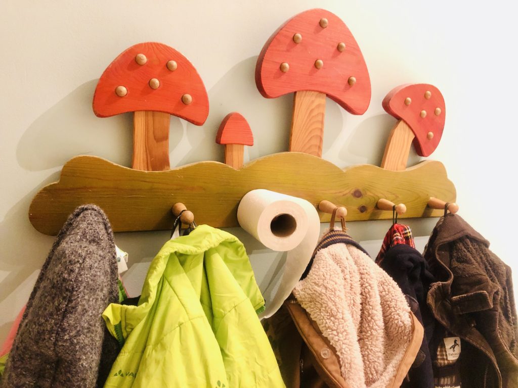 Klopapierrolle hängt an Kindergarderobe mit Pilzen
