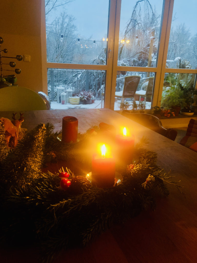 Adventskranz mit Fenster und Schnee im Hintergrund